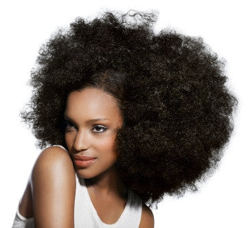 A woman with voluminous, natural black Type 4 hair smiles softly, looking slightly to the side.