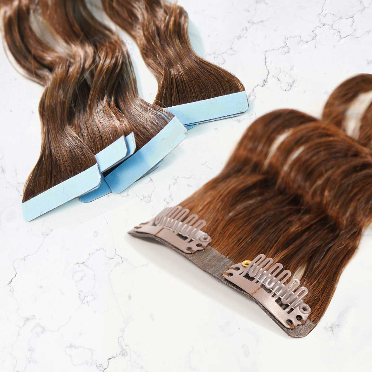 Two types of brown Hair Extensions are shown on a white surface: Tape-In Extensions with blue tape tabs and Clip-In Extensions featuring metal combs.