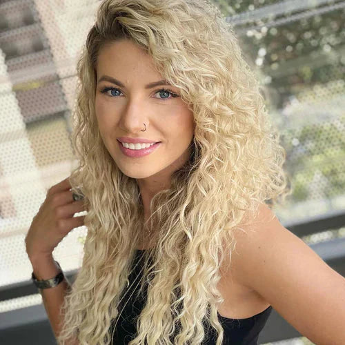 A woman with long, curly hair and a nose ring smiles at the camera.