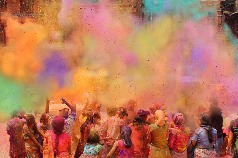 A group of people celebrate Holi, the vibrant spring festival of color, by tossing colored powders into the air.