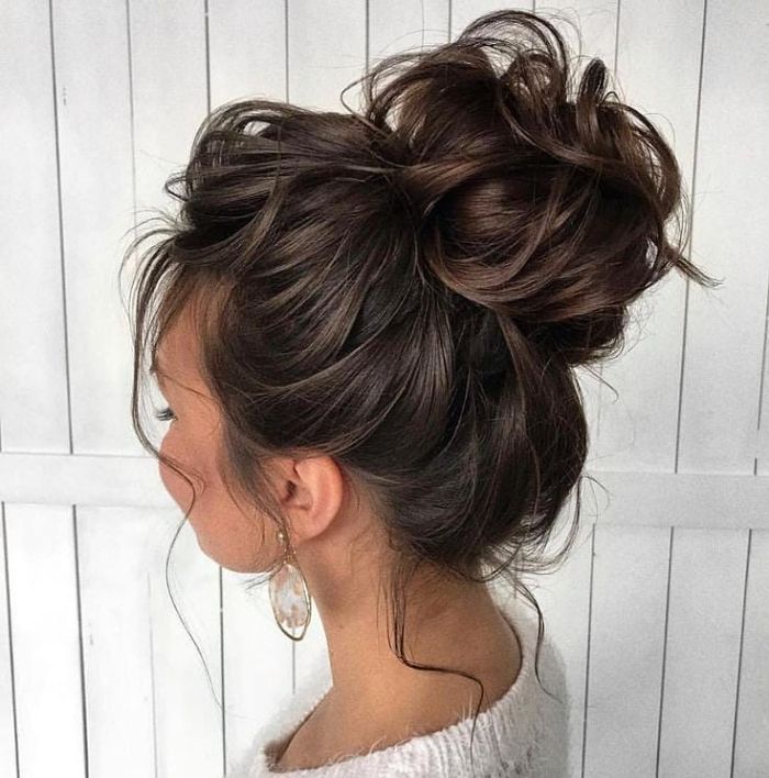 A woman with brunette hair styled in a voluminous, messy bun, one of the perfect quick hairstyles for busy mornings.