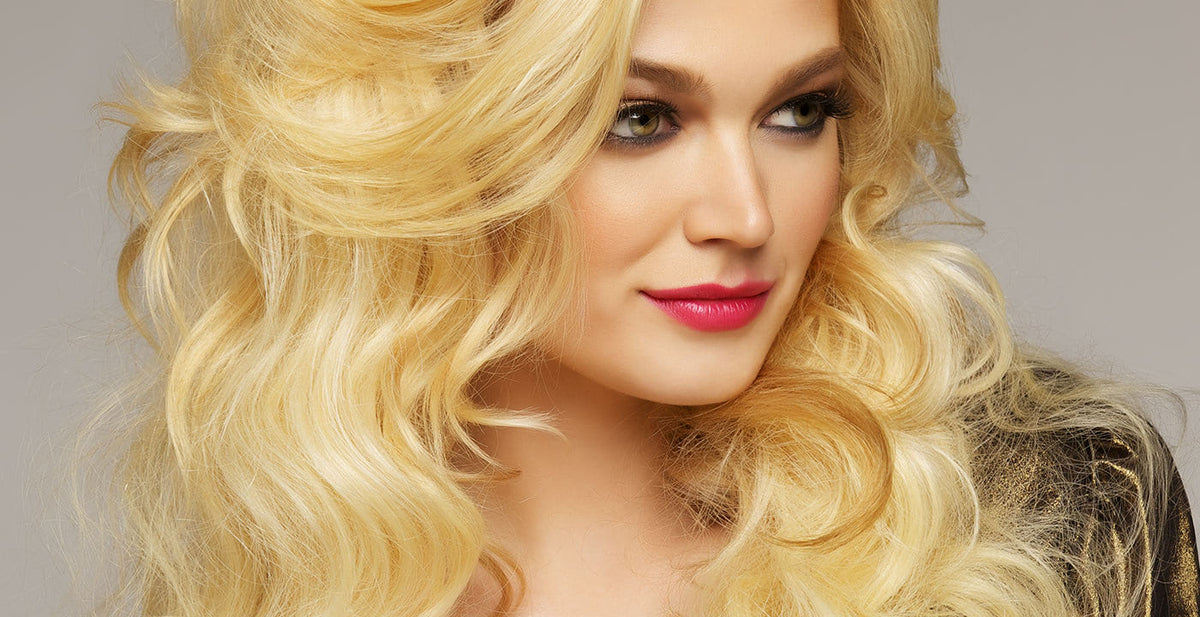 Woman with long, voluminous Perfect Locks blonde wavy hair extensions and bold pink lipstick