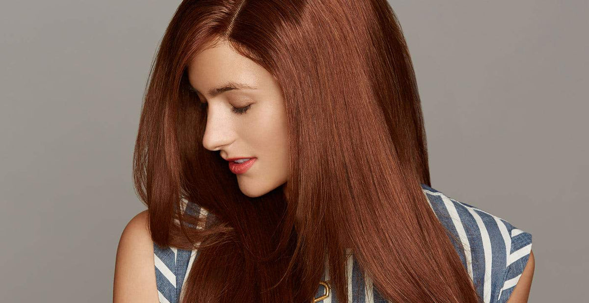 Woman wearing a Perfect Locks caucasian wig with long, straight auburn hair and a gentle smile