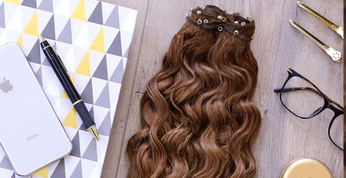 Perfect Locks micro link hair extensions in wavy brown displayed with styling accessories on a desk