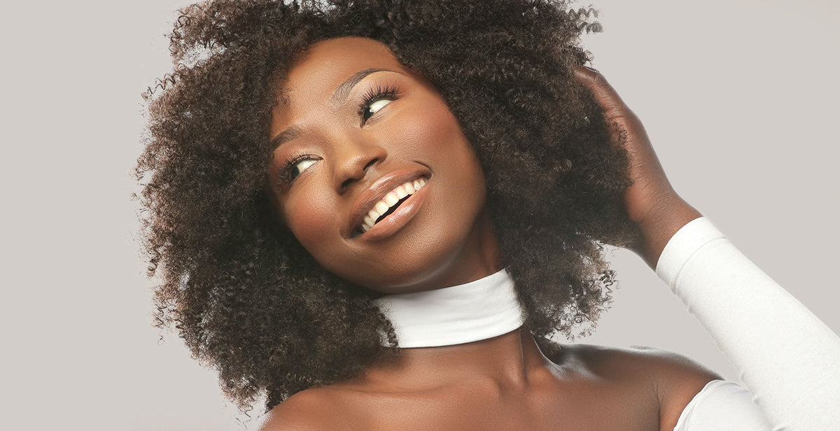 Woman with natural curly hair in Perfect Locks short sew-in weaves and a white off-shoulder top