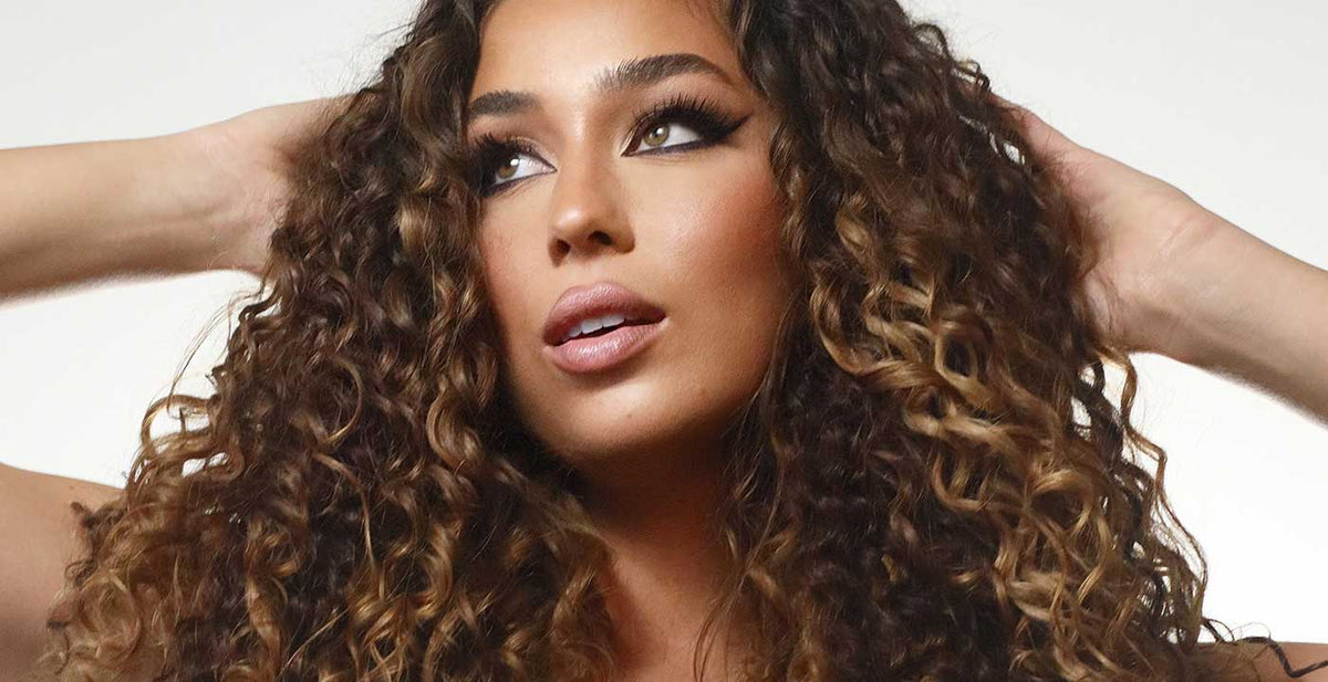 Woman with voluminous curly brown Perfect Locks tight curly hair extensions with highlights