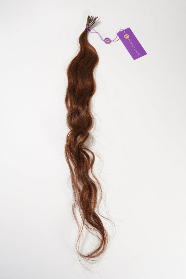 A long, wavy brown hair extension with a purple tag at the top rests on a white background, offering a natural and stylish look.