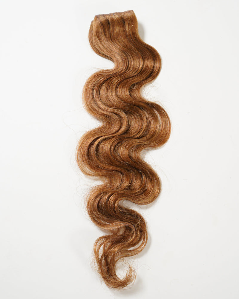 A long, wavy lock of light brown hair extension with soft, defined waves and a smooth texture is displayed on a white background.