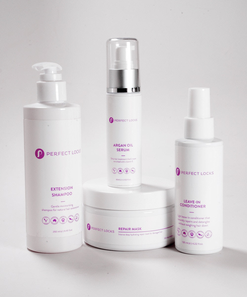 The Perfect Locks Dry Hair Reviver Bundle for extensions with Extension Shampoo, Argan Oil Serum, Repair Mask, and Leave-In Conditioner in white bottles with purple and gray text.