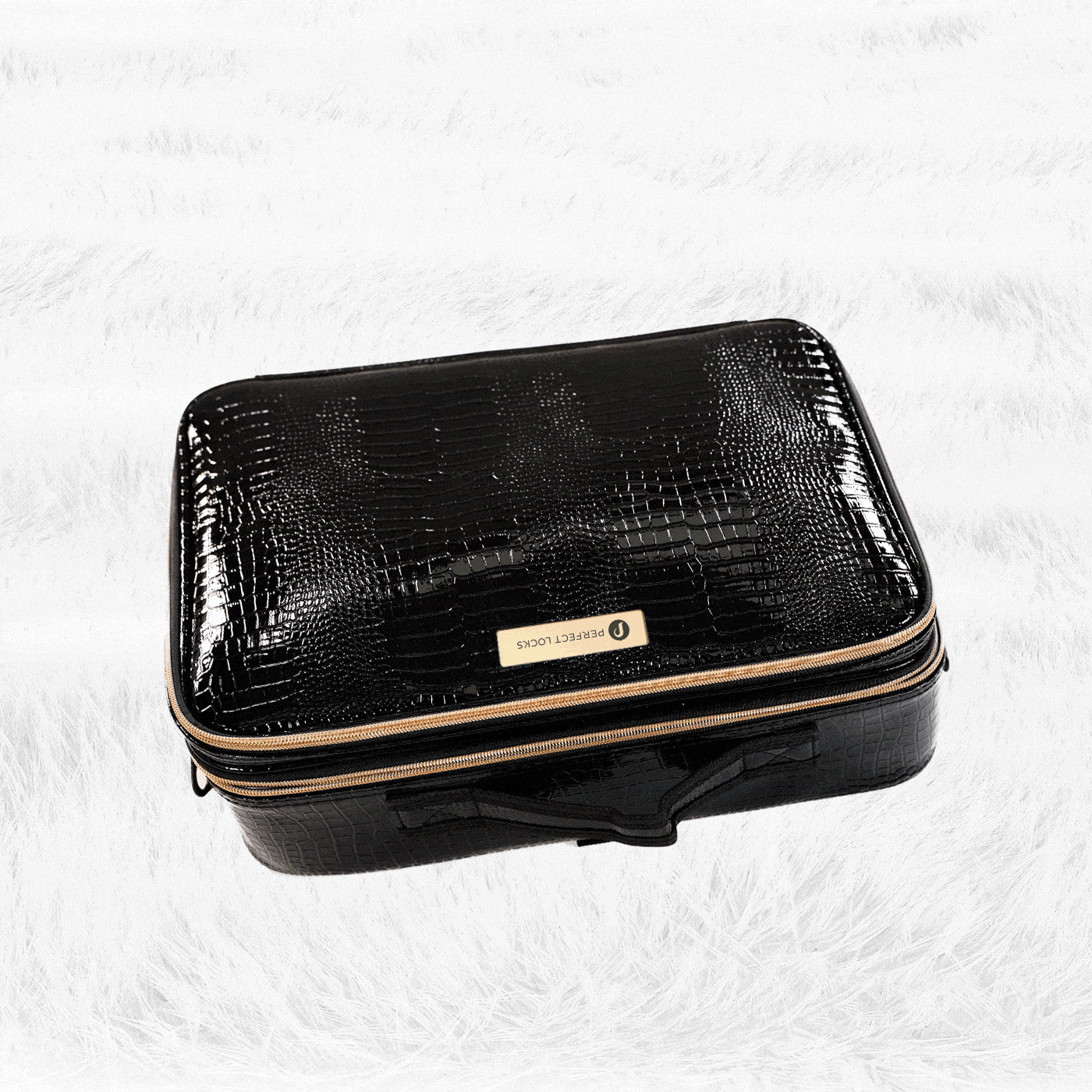 A black, textured rectangular travel case with a gold zipper and TRAVELLOCUS label sits on a white, fluffy surface.