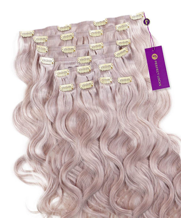 A set of Wavy Seamless Clip-In Hair Extensions by Perfect Locks in Rooted Toffee Blonde Highlights, arranged in rows with gold clips and a purple Perfect Locks tag attached to one extension.#color_metal-gray-(60S)