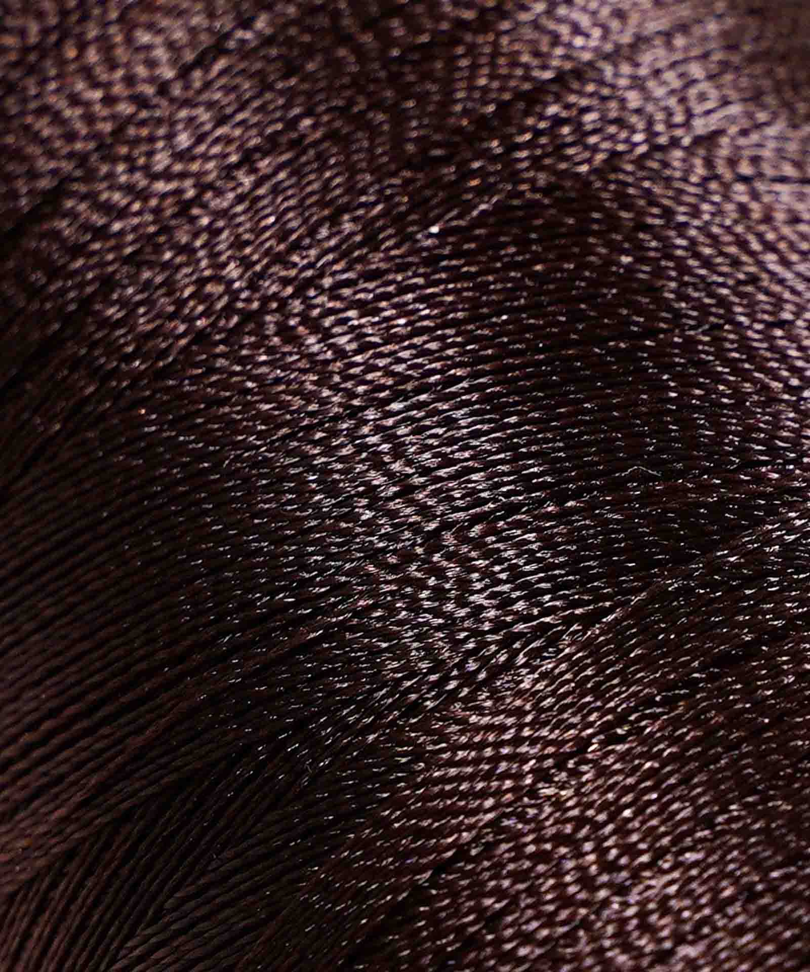 Tightly wound, shiny dark brown thread reveals intricate texture and fine strands, highlighting the rich detail of the material.