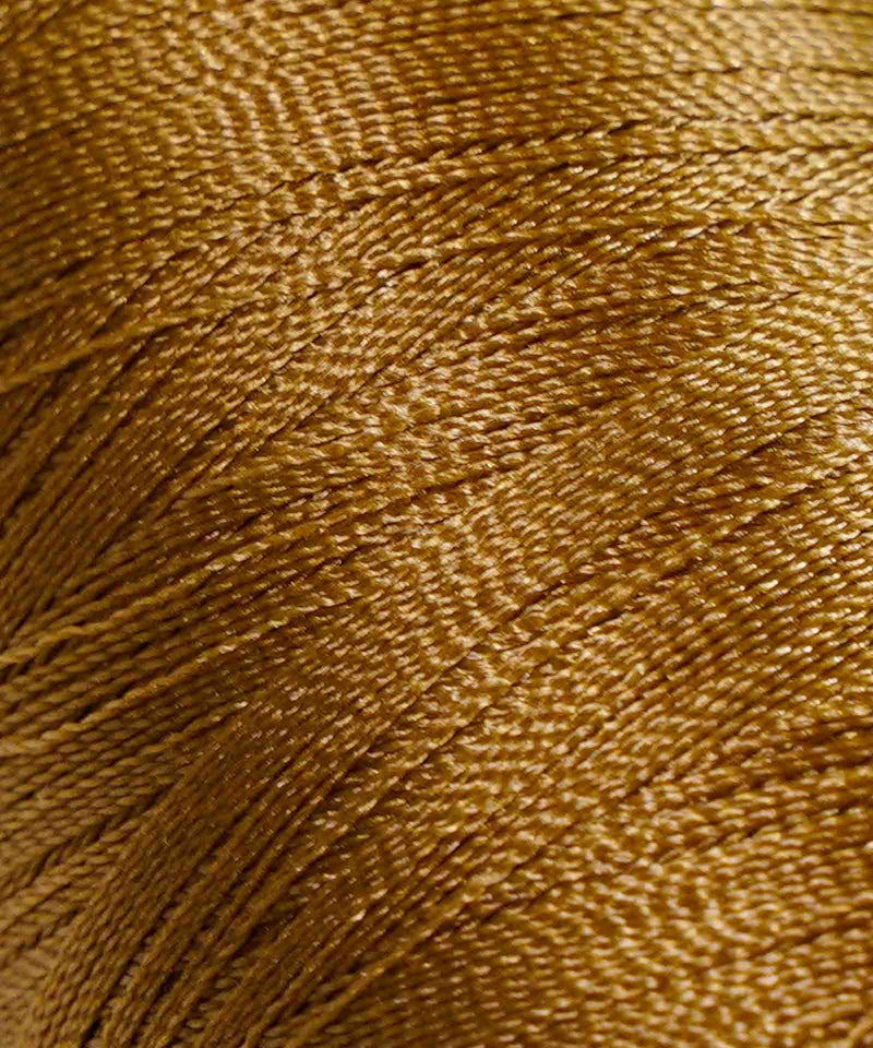 Close-up of tightly wound golden brown thread, highlighting its smooth, shiny texture and fine fibers in diagonal lines as a textile background.