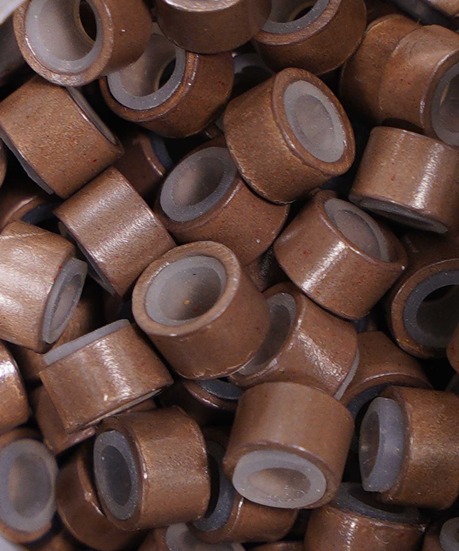 Close-up of Perfect Locks Fusion Micro Ring Beads in dark brown, small hollow cylindrical beads, stacked and scattered for hair extensions.#color_dark-brown-(4)