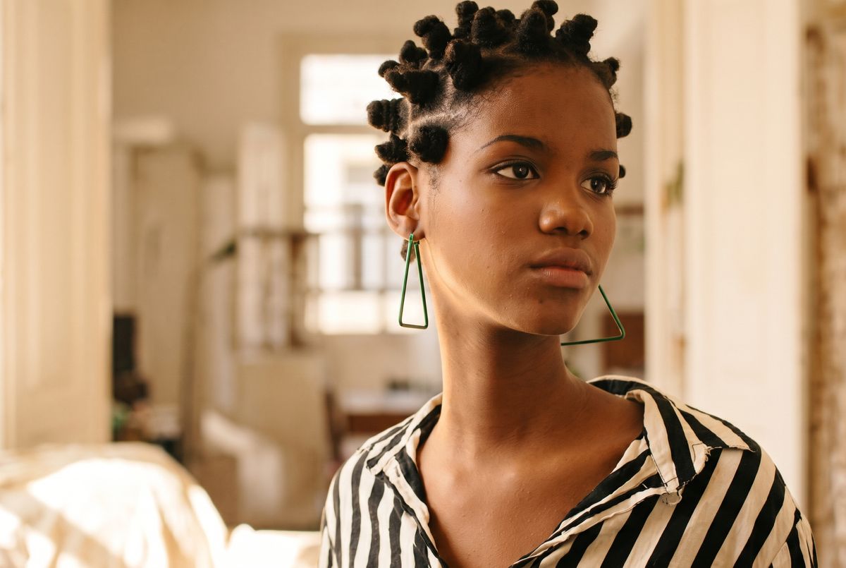 Woman with neat Bantu knots in sectioned parts, shown from the side to highlight the knot pattern