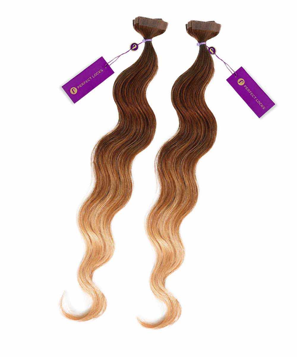 Two bundles of long, wavy hair extensions feature a beautiful brown to blonde ombre, each tied with a purple Perfect Locks tag.