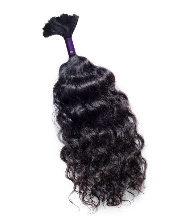 A bundle of curly bulk hair extensions tied at the end with a purple band.