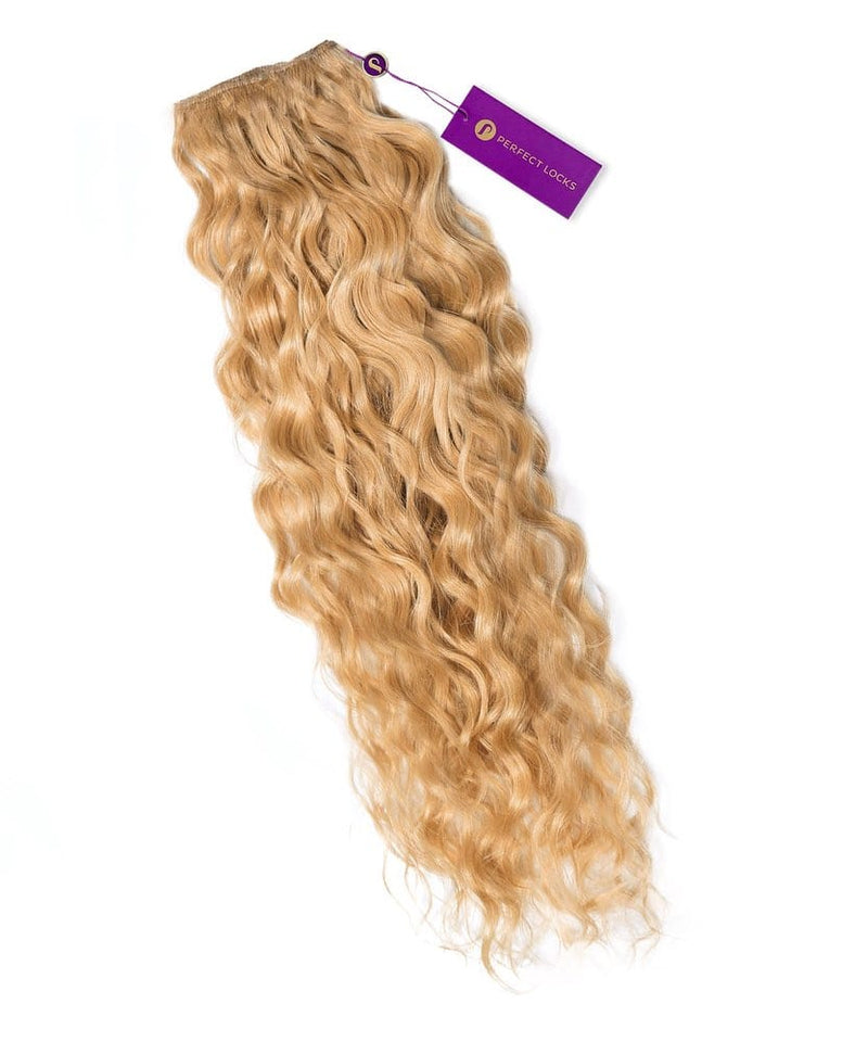 A bundle of honey blonde Curly Colored Hair Machine Weft extensions from Perfect Locks with a purple tag on a white background.