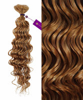 A bundle of Perfect Locks Curly Invisi Tape In Hair Extensions in Highlighted Brown Auburn, tied with a purple ribbon and tag.#color_honey-blonde-(27)