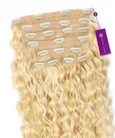Curly Classic Clip-In Hair Extensions by Perfect Locks in Platinum Blonde are spread out, with a purple tag on one weft.#color_platinum-blonde-(613)