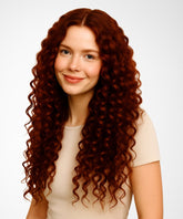 A young woman with long, curly Dark Auburn hair wears the Perfect Locks Curly U-Part Wig and a beige top, smiling gently against a white background.#color_dark-auburn-(33)