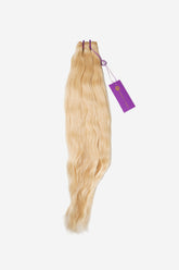The Perfect Locks Wavy Machine Weft in 18" Sunny Blonde features long, wavy Remy hair extensions with purple bands and a tag on white background.#color_sunny-blonde.