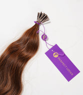 A bundle of brown wavy hair extensions with metal tips, tied with a purple string and a tag labeled Perfect Locks in gold letters.