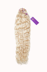 Long, wavy, light blonde hair extensions secured with purple bands and a purple tag, perfect for adding volume and length to your look.