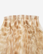 Blonde wavy hair extension with lace or weft top, shiny natural texture, and loose waves for added volume.