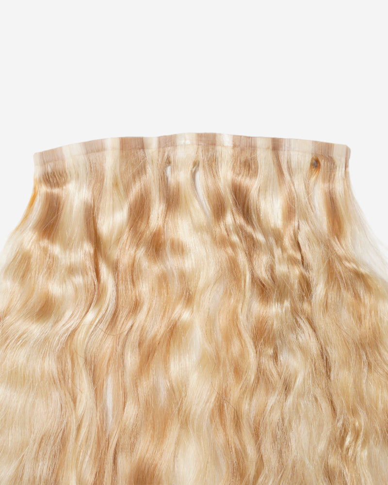 Blonde wavy hair extension with lace or weft top, shiny natural texture, and loose waves for added volume.