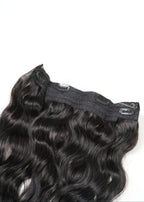 A close-up of a wavy, dark brown clip-in hair extension shines against a plain white background, highlighting its natural-looking texture.