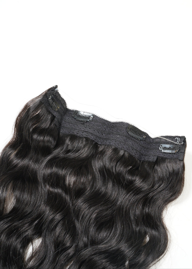 A close-up of a wavy, dark brown clip-in hair extension shines against a plain white background, highlighting its natural-looking texture.