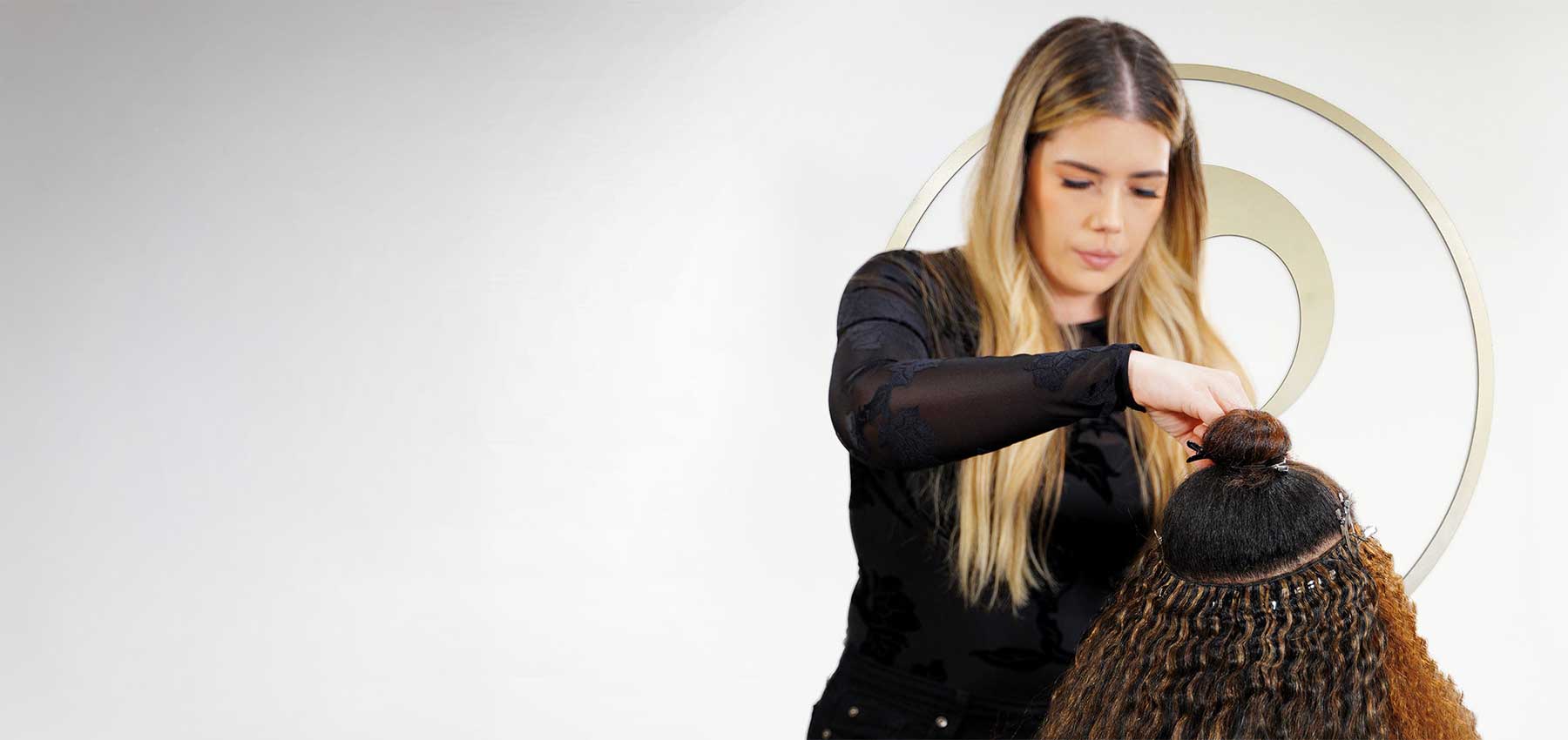 Woman working with a bundle of braided hair on a plain background