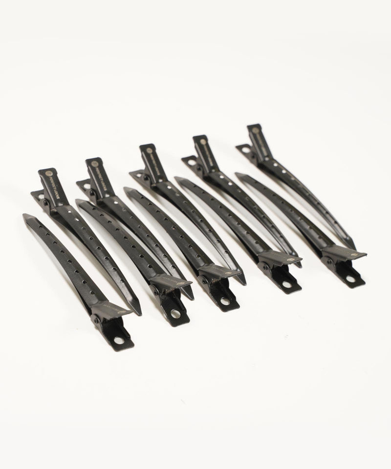 Six black hair sectioning clips are arranged in two neat rows on a white background, each with holes and a secure spring mechanism.