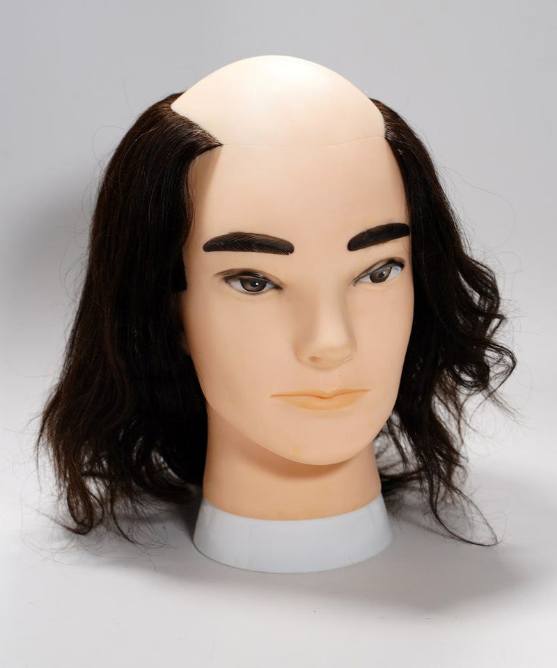 A mannequin head with realistic features, thick dark eyebrows, long dark side hair, and a bald top against a simple background.
