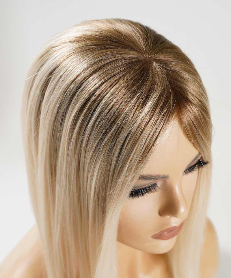 The Perfect Locks Straight Human Hair Crown Topper with rooted ash blonde color, long straight hair, smooth skin, defined brows, closed lips, and long eyelashes.