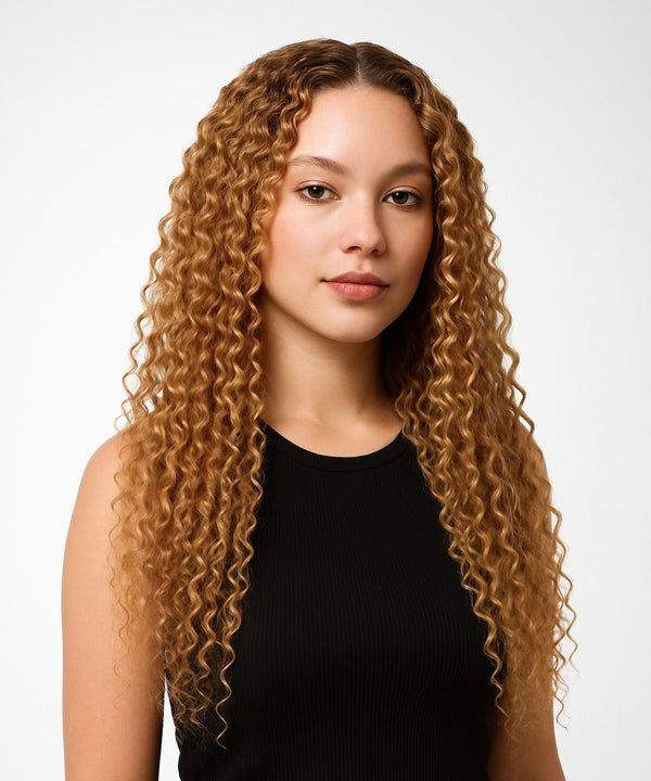 Woman with long, wavy blonde hair wearing a black top on a white background