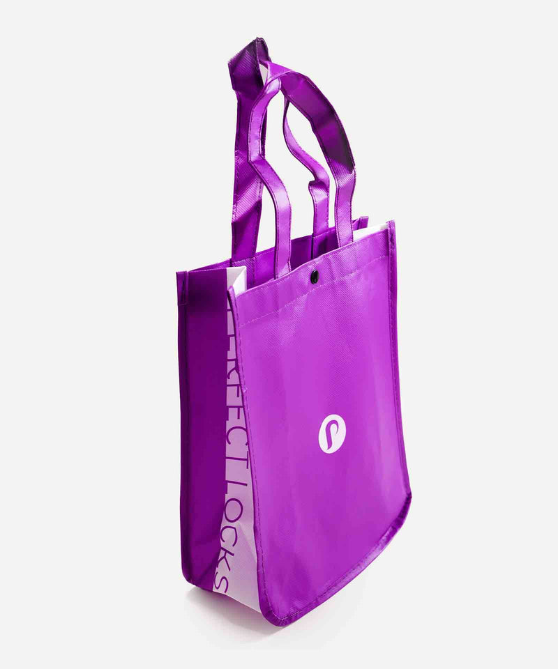 The Perfect Locks purple tote bag with two handles, white circular front logo, and Remy hair extensions text stands on a white surface.