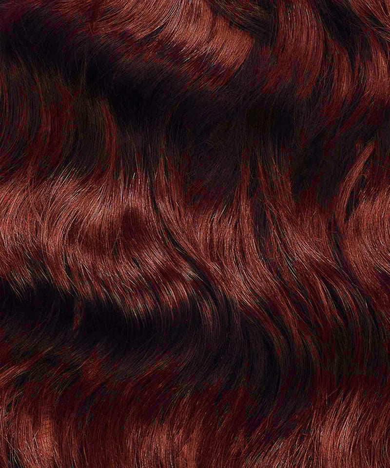 Close-up of wavy, shiny golden brown  hair with highlights and lowlights, enhanced with I-Tip extensions for texture and movement.