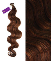 A bundle of long, wavy Perfect Locks Wavy Hybrid Weft Hair Extensions in Ice Blonde with highlights beside a close-up of the texture. A purple Perfect Locks tag is attached to the bundle.#color_highlighted-brown-auburn-(30/31/33)