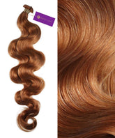 A close-up of wavy, shiny, Honey Blonde Wavy Hybrid Weft Hair Extensions from Perfect Locks with a purple tag attached.#color_honey-blonde-(27)
