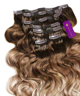 Perfect Locks Wavy Seamless Clip-In Hair Extensions in pearl bronde balayage blend from dark roots to lighter ends, with a purple Perfect Locks tag on one bundle.#color_pearl-bronde-balayage-(3/8/613)