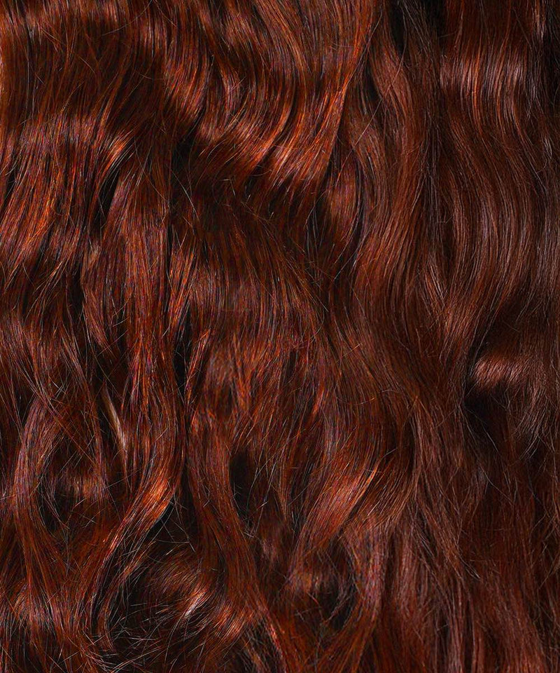 Close-up of wavy, shiny dark auburn hair with rich red and brown tones, enhanced by clip-in ponytail extensions in color 33.
