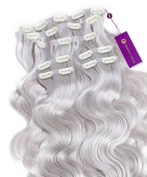A set of silver Perfect Locks Wavy Seamless Clip-In Hair Extensions with white clips is fanned out, purple tag attached to a corner.#color_silver-(S)