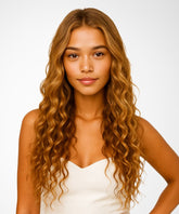 A young woman with long, wavy Golden Brown hair wears the Perfect Locks Wavy U-Part Wig and a white sleeveless top, standing against a plain white background and looking calmly at the camera.#color_golden-brown-(6)