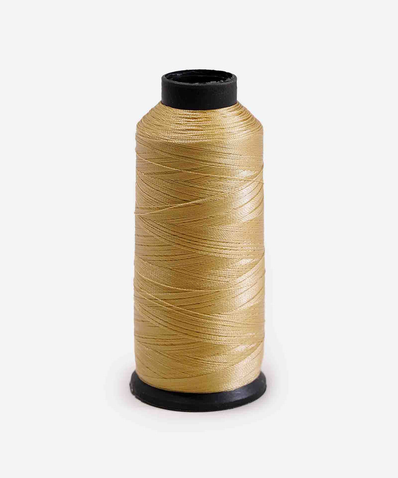 A spool of light beige thread tightly wound around a black plastic reel stands upright against a plain white background, perfect for sewing projects.