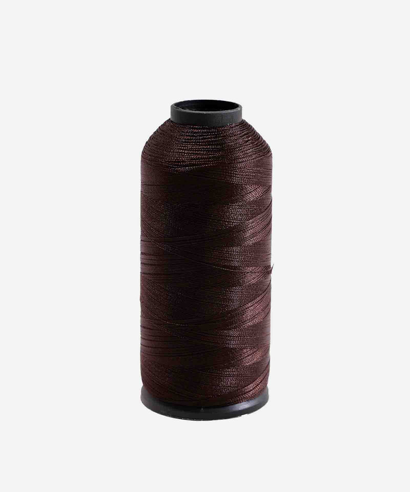 A spool of dark brown sewing thread stands upright on a white background, neatly wound on a cylindrical plastic core with black ends.