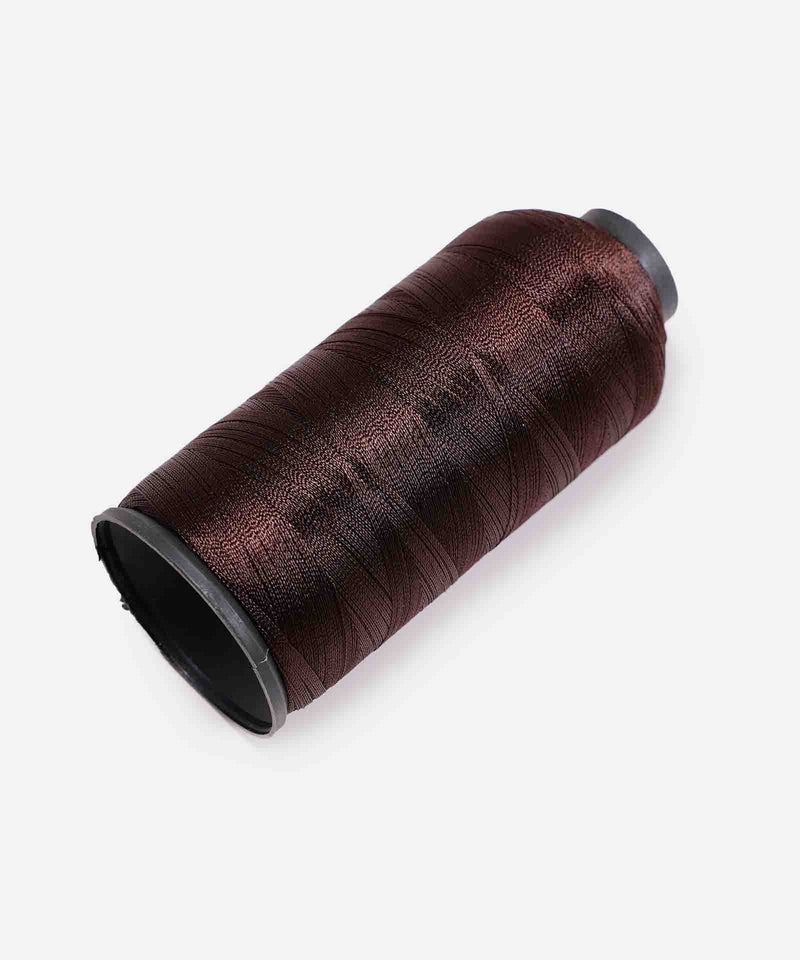 A spool of dark brown thread rests on its side against a white background, perfect for sewing or crafting projects.
