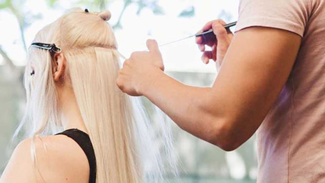 stylist installing tape ins on client