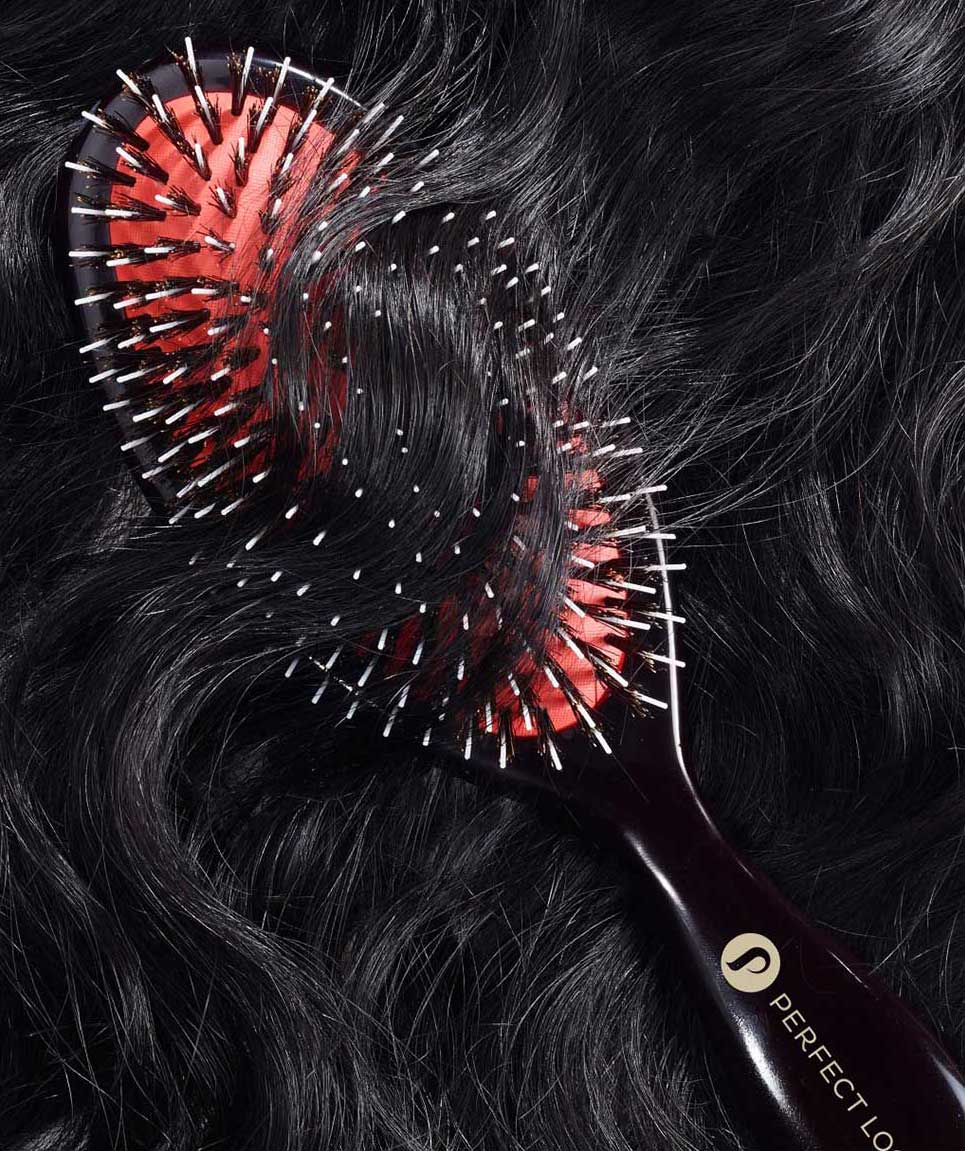 Hairbrush with red bristle head on black hair extensions